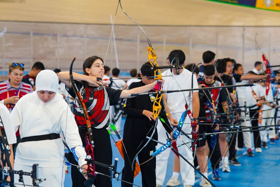 Atış hattında yan yana dizilmiş sporcular olimpik yaylarla nişan alıyor