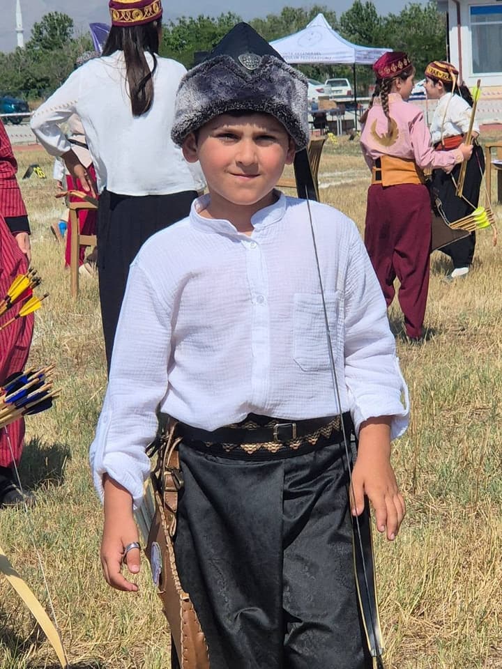 Geleneksel okçu kıyafeti ve börkle genç sporcu, yarışma alanında