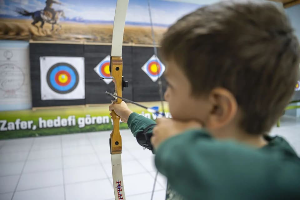 Küçük sporcu ahşap gövdeli başlangıç yayıyla nişan alıyor